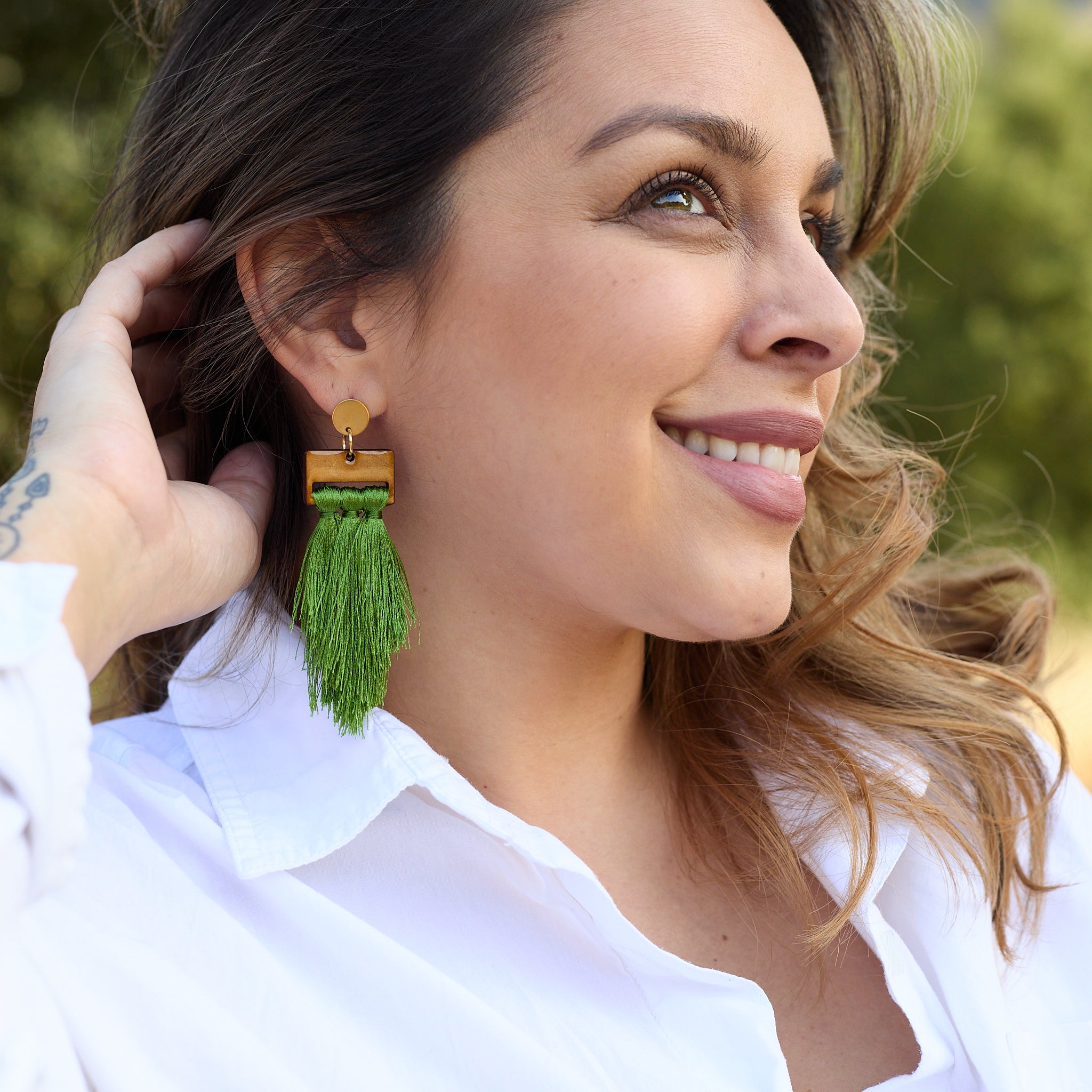 Woman wearing a green tassel earring outdoors